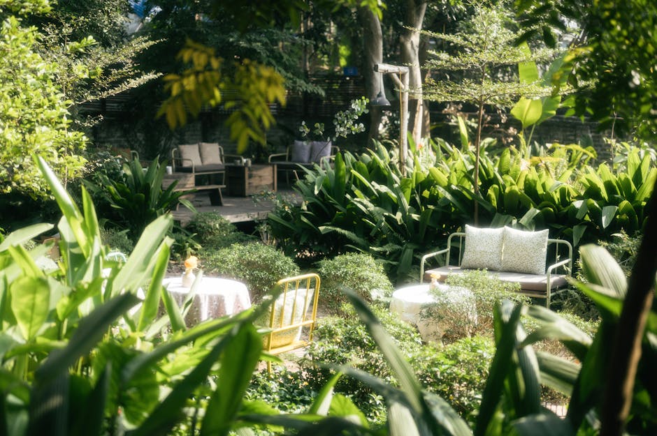 A neatly maintained small city garden near Temple station, showcasing a well-trimmed hedge with lush green foliage along the boundary. The garden features a vibrant green lawn with freshly mowed grass